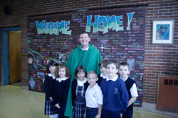 WELCOME HOME Father David Boettner receives a warm welcome from students at Sacred Heart Cathedral School who were showing him the graffiti wall they made for him. Standing with Father Boettner are (from left) Kate Bosi, Skylar Fortich, Camille Hunt, Caiden Slater, Bentley Turbyville, Hayden Oliver, and Andrew Medlyn. Photo by Dan McWilliams