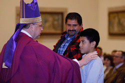 WELCOME TO THE CHURCH Bishop Richard F. Stika greets catechumen Alonzo Creech during the Rite of Election at St. John Neumann Church on Feb. 16. Accompanying Alonzo is his godparent, Avelardo Mercado. Photo by Dan McWilliams
