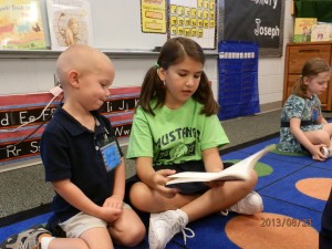 St. John Neumann preschool student Reese Drone listens to his fourth-grade buddy, Isabella Ramos, as she reads a book. Photo by Michelle Dougherty 