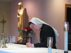 Sister Seán Marie Striby, RSM, signs her vows on the altar during Mass on Aug. 15 in Alma, Mich.
