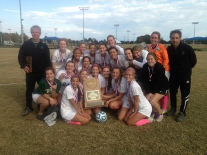 WITH THE CHAMPIONSHIP HARDWARE The Lady Irish soccer team gathers around the first-place trophy after defeating Christian Academy of Knoxville for the state title. Courtesy of Knoxville Catholic High School