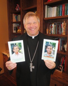 Bishop Richard F. Stika holds photos of two children he is sponsoring through Nuestros Pequeños Hermanos, which cares for abandoned and orphaned children in Central America.