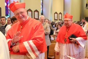 Cardinal Timothy Dolan waves to the assembly at Sacred Heart Cathedral as he processes in to Mass just ahead of Cardinal William Levada. Photo by Dan McWilliams