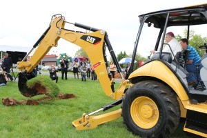 Bishop Richard F. Stika operates a backhoe to remove a scoop of dirt at the Sacred Heart Cathedral groundbreaking. Photo by Dan McWilliams