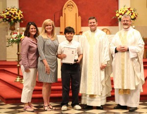 Kai Ringle received the Specialist Ty M. Carter Challenge Coin at Sacred Heart Cathedral on May 22. With him are (from left) Sacred Heart teacher Theresa Ciancone, Principal Sarah Trent, cathedral rector Father David Boettner, and associate pastor Father Joe Reed. Photo by Dan McWilliams