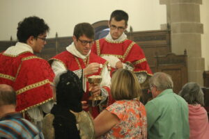 priest offers Eucharist to kneeling parishioner