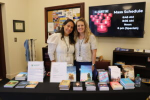 Two women standing at table of books