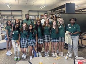 Group of students in uniform pose in library