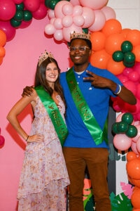 Woman and man in crowns pose in front of balloons