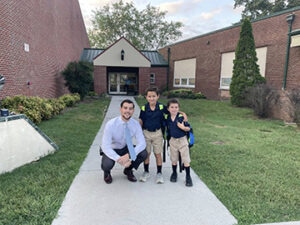 Principal and two young students pose outside of school