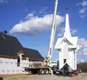 Church steeple being lifted by crane